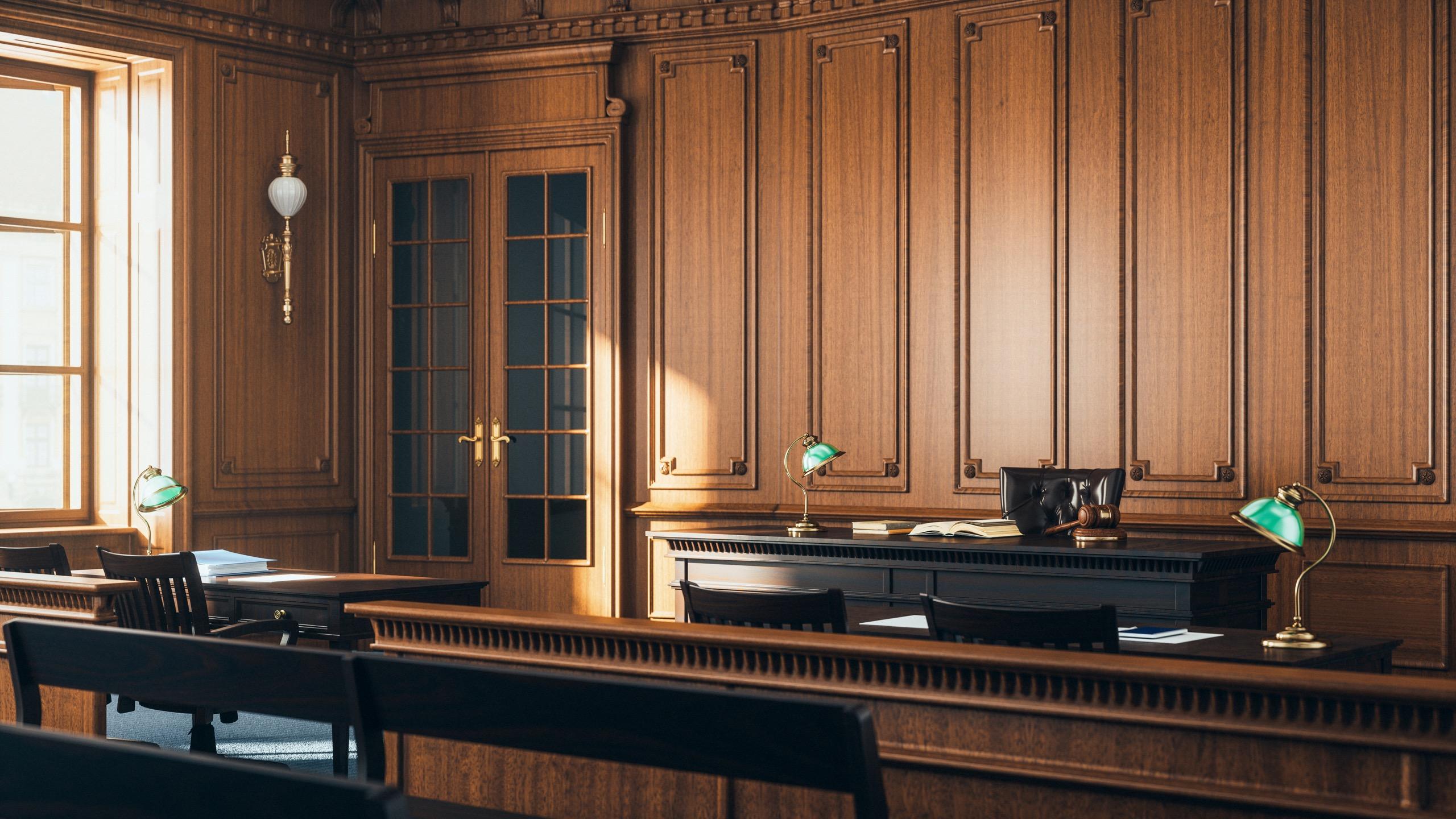 Empty wooden courtroom with judge’s bench, gavel, and desks.